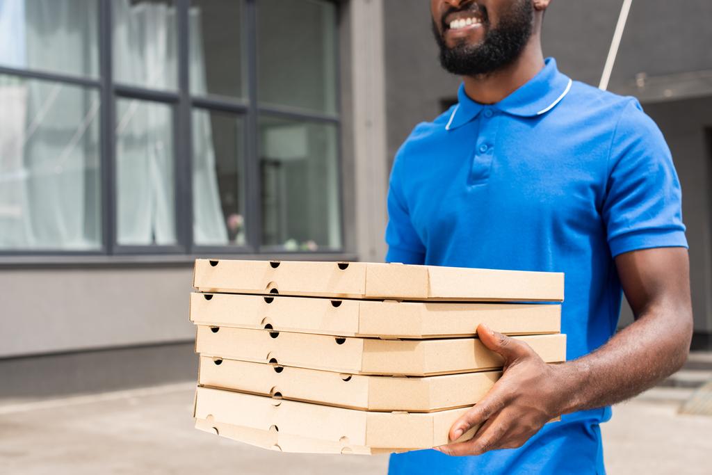 ピザの箱を運ぶアフリカ系アメリカ人の配達人の画像をトリミング - 写真・画像