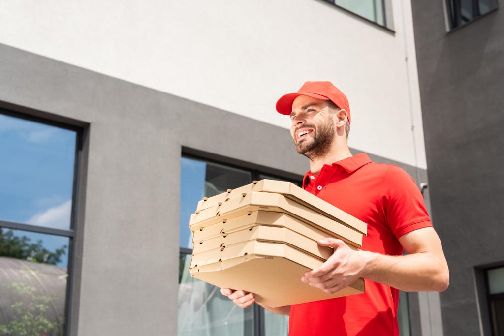 vue à angle bas du livreur caucasien portant des boîtes à pizza
 - Photo, image