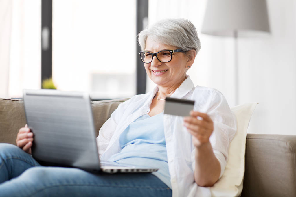 Старшая женщина с ноутбуком и кредитной картой дома - Фото, изображение
