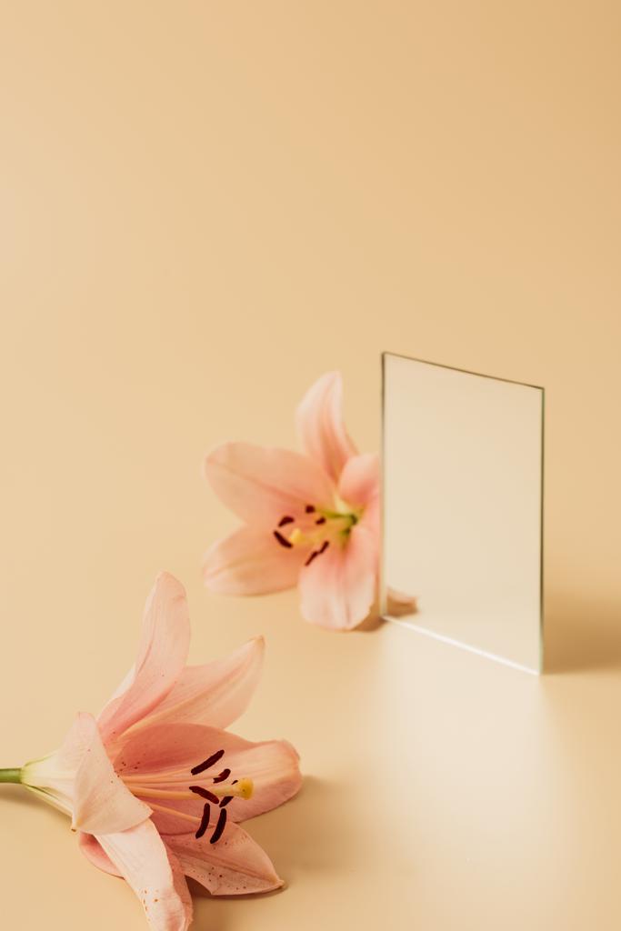 two lily flowers and mirror on beige table  - Photo, Image