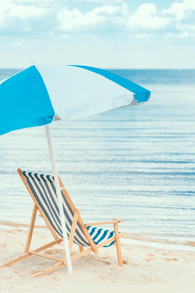 夏の海辺に青い太陽の傘とビーチの椅子 - 写真・画像