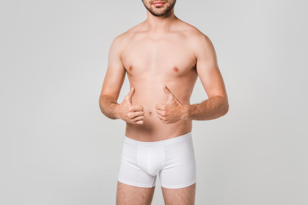 osittainen näkymä mies valkoisissa alusvaatteissa osoittaa peukalot ylös eristetty harmaa
 - Valokuva, kuva