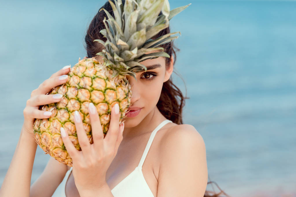 muotokuva houkutteleva tyttö bikinit tilalla tuoretta ananasta lähellä merta
 - Valokuva, kuva