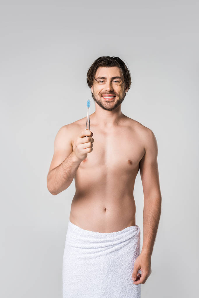 retrato de homem alegre em toalha branca com escova de dentes isolada em cinza
 - Foto, Imagem