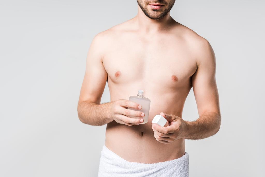 bijgesneden schot voor man in een witte handdoek met mannelijke parfum geïsoleerd op grijs - Foto, afbeelding