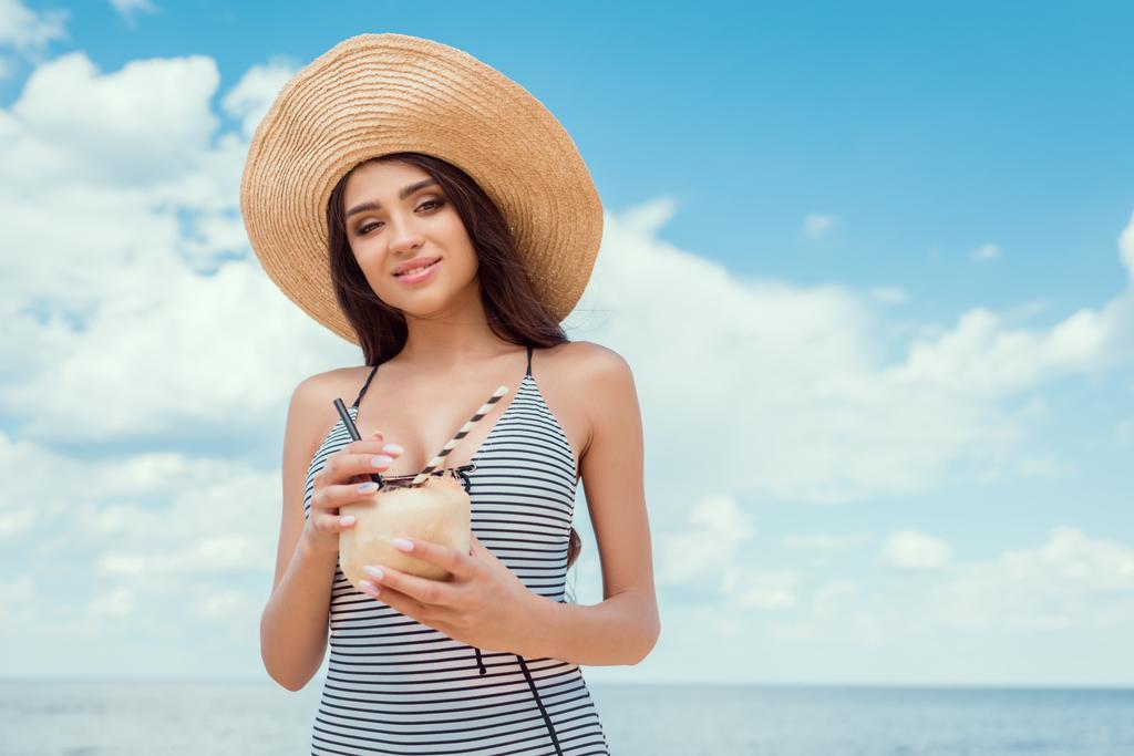 attractive girl in straw hat holding green coconut with straws - Photo, Image