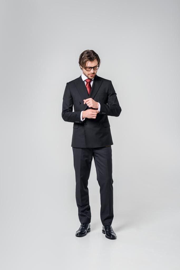 jovem empresário em terno elegante e óculos em pano de fundo cinza
 - Foto, Imagem
