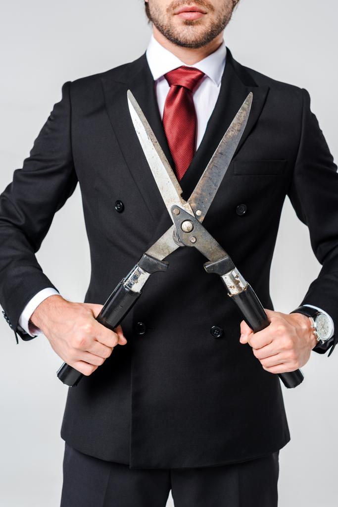 περικοπεί shot του επιχειρηματία σε μαύρο κοστούμι με clipper στα χέρια που απομονώνονται σε γκρι - Φωτογραφία, εικόνα