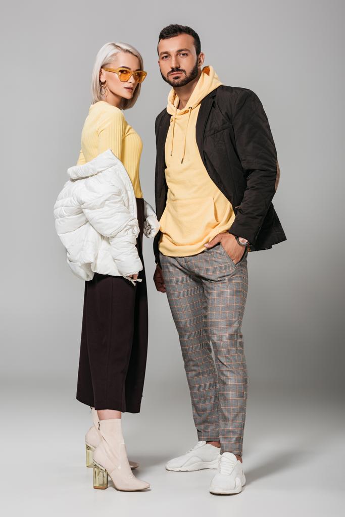 νεαρό ζευγάρι μοντέλων κομψά Φθινοπωρινά Ρούχα θέτοντας σε γκρίζο φόντο  - Φωτογραφία, εικόνα