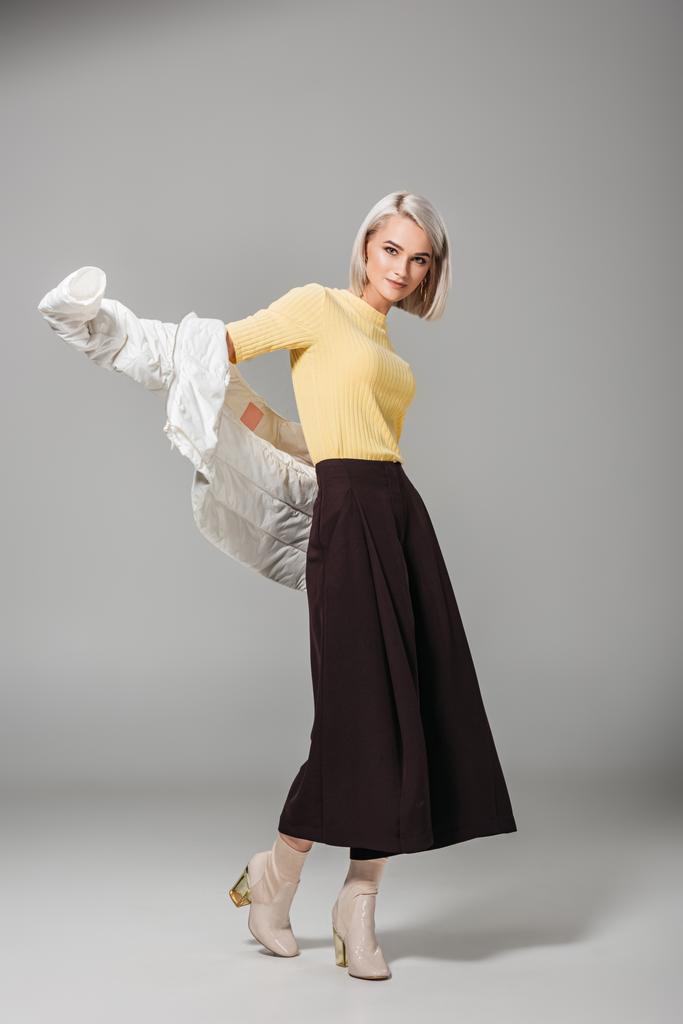 красивая женщина модель надевает стильный белый осенний пиджак изолирован на сером фоне
  - Фото, изображение