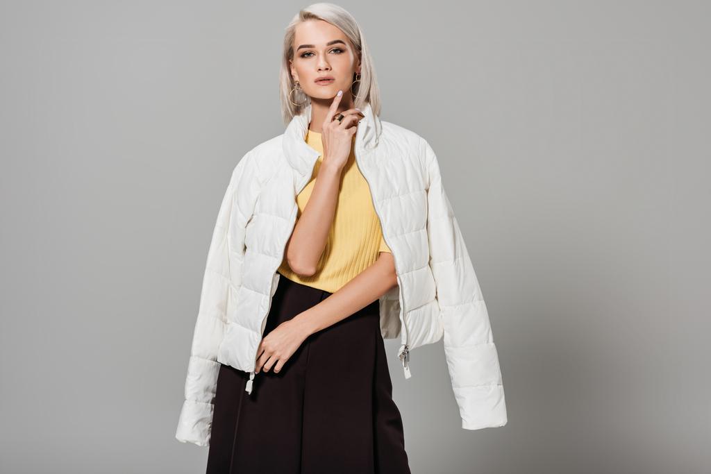 впевнена молода жіноча модель в білій куртці над плечима позує ізольовано на сірому фоні
 - Фото, зображення