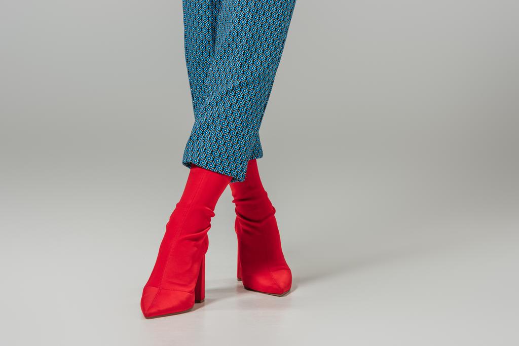 cropped image of female models legs in red stylish boots on grey background  - Photo, Image
