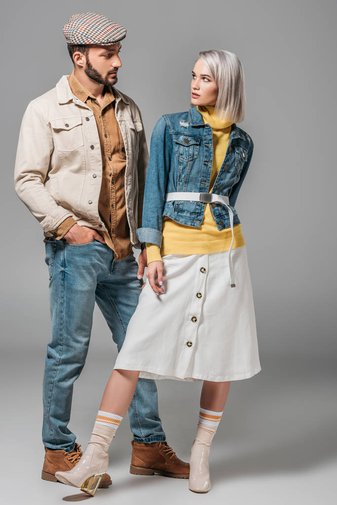 Paar posiert im Herbst-Outfit und schaut sich an, auf grau - Foto, Bild