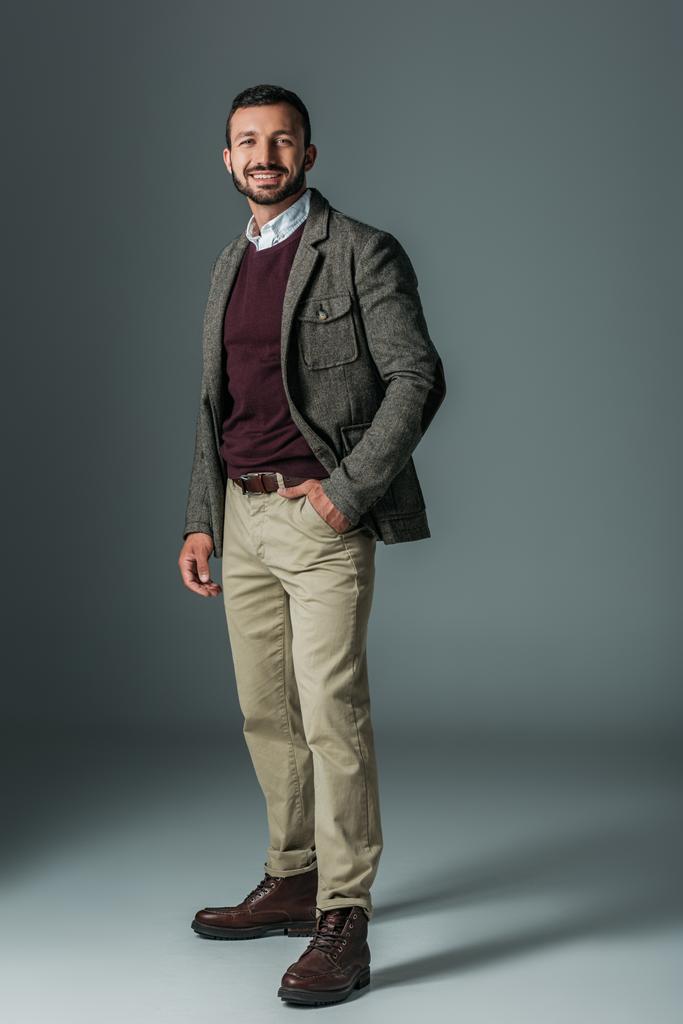 elegante modello maschile in posa in pantaloni beige e giacca in tweed, su grigio
 - Foto, immagini
