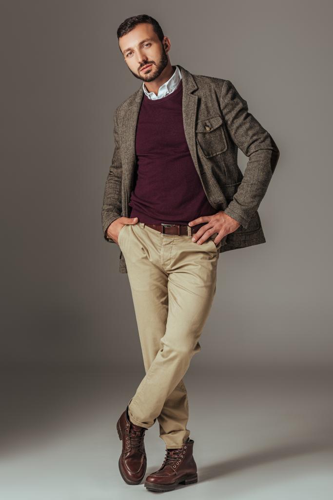 όμορφος μοντέρνος άνθρωπος που θέτουν σε φθινόπωρο τουίντ σακάκι, σε γκρι - Φωτογραφία, εικόνα