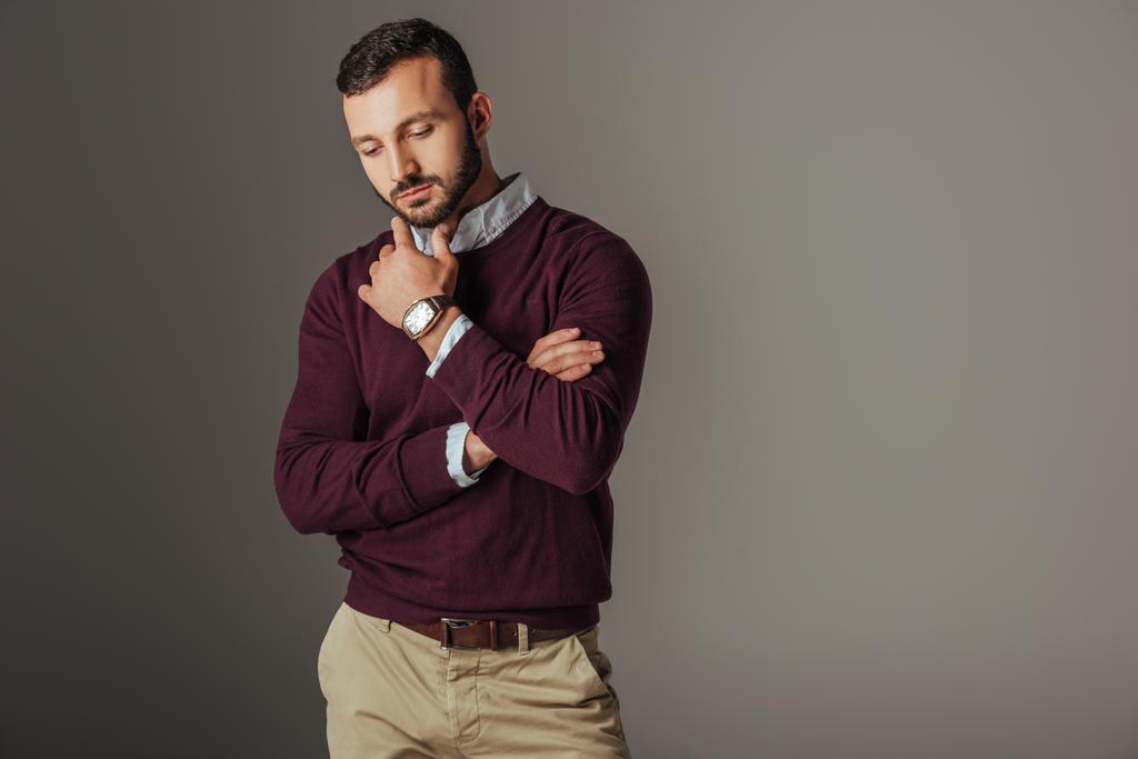 вдумчивый красивый мужчина-модель позирует в бордовом свитере, изолированный на сером
 - Фото, изображение