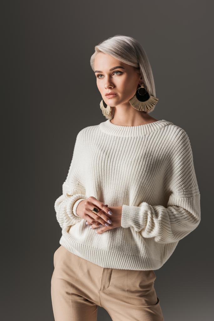 привлекательная девушка позирует в белом осеннем свитере и круглых серьгах, изолированных на сером
 - Фото, изображение