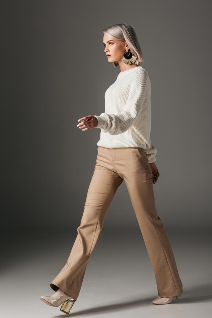 moda kız beyaz süveter, gri ve bej pantolon yürüyüş - Fotoğraf, Görsel