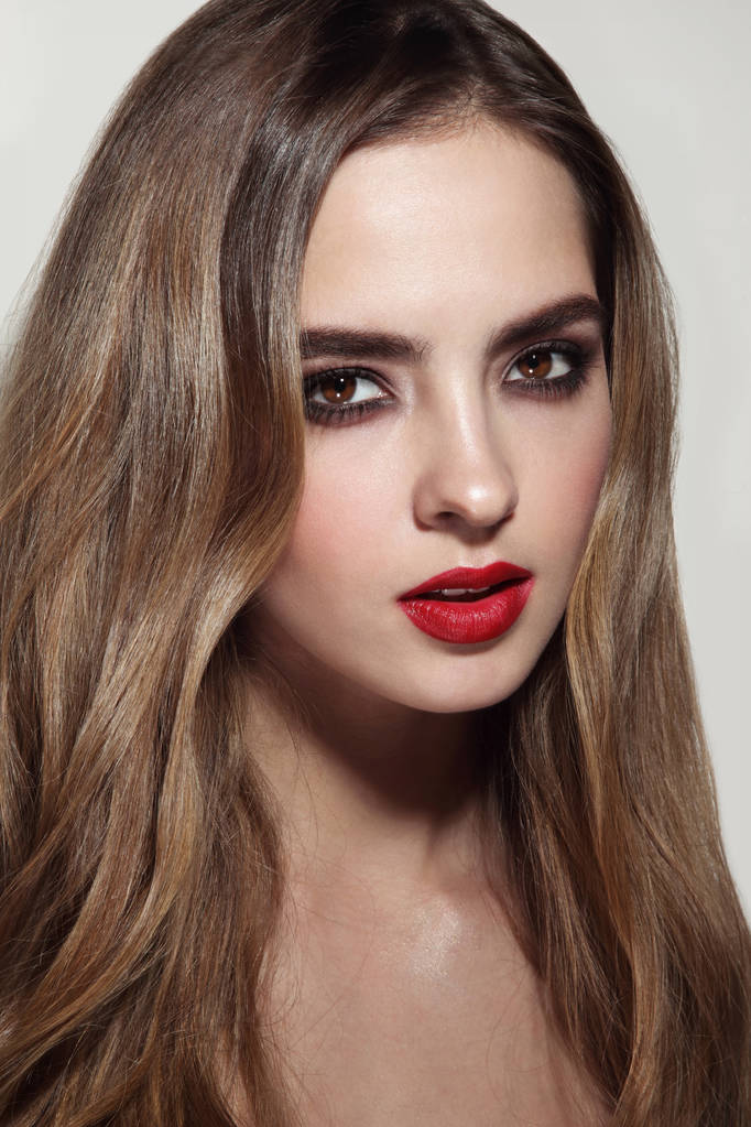 junges schönes Mädchen mit langen lockigen Haaren und rotem Lippenstift - Foto, Bild