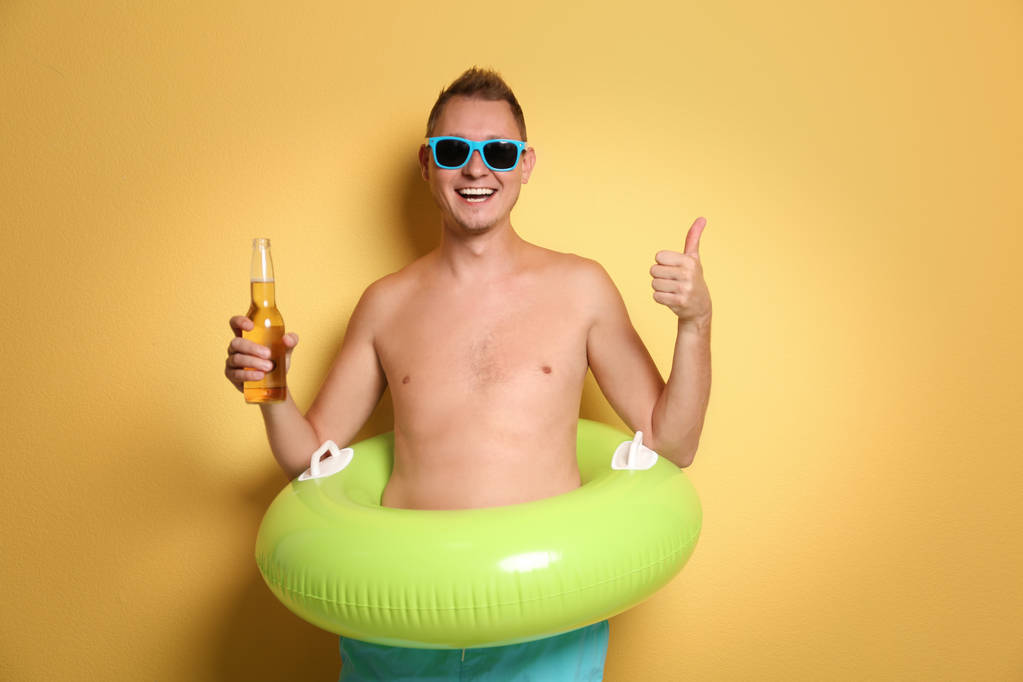 Homme torse nu avec anneau gonflable et bouteille de boisson sur fond de couleur
 - Photo, image