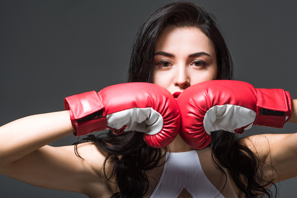 Frau in Boxhandschuhen blickt vereinzelt in die Kamera  - Foto, Bild