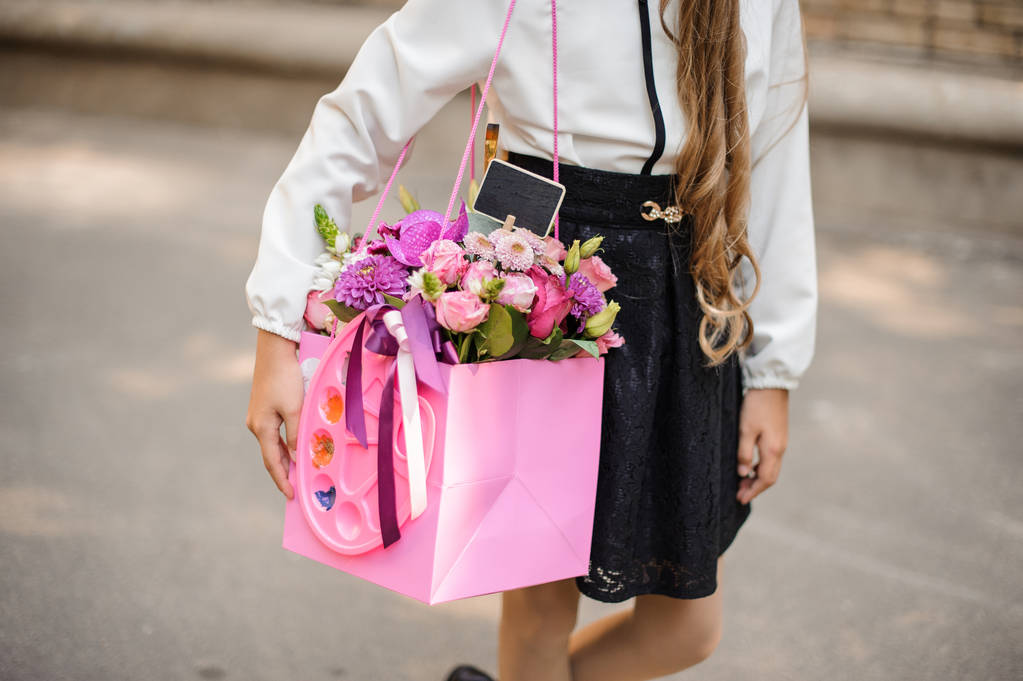 明るいピンクのお祝い花束を保持している学校の制服に身を包んだ女子校生 - 写真・画像