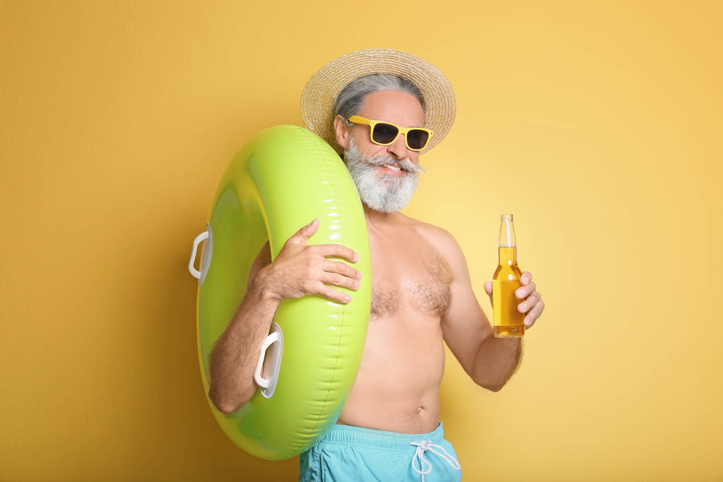 インフレータブル リングと色の背景上の飲み物のボトルと上半身裸の男 - 写真・画像
