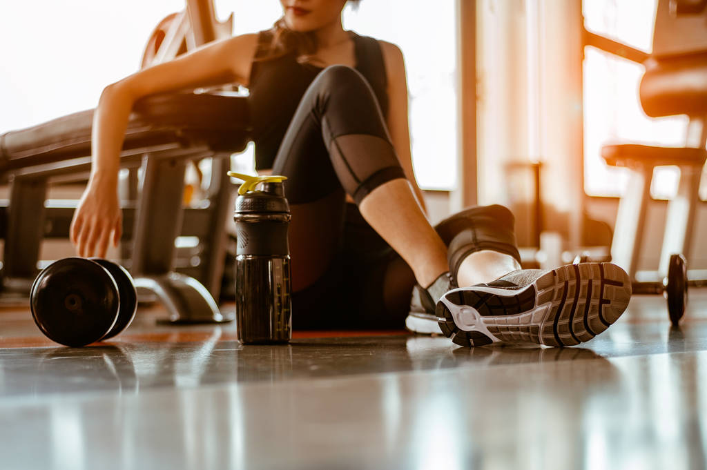 Relaxing after training.beautiful young woman looking away while sitting at gym. young female at gym taking a break from workout.. - Photo, image