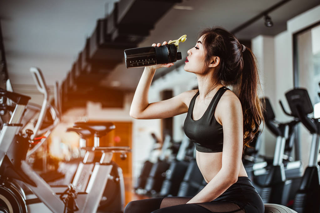 giovane donna di fitness stanca in palestra bere proteine shake.exercising concept.fitness e stile di vita sano  - Foto, immagini