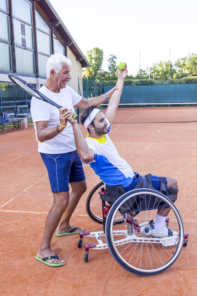 Tennistrainerin bringt einem behinderten Spieler die korrekte Bewegung des Service bei - Foto, Bild