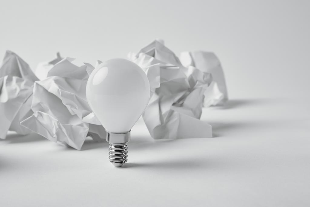 крупним планом знімок енергозберігаючої лампочки зі збитими паперами на білому
 - Фото, зображення