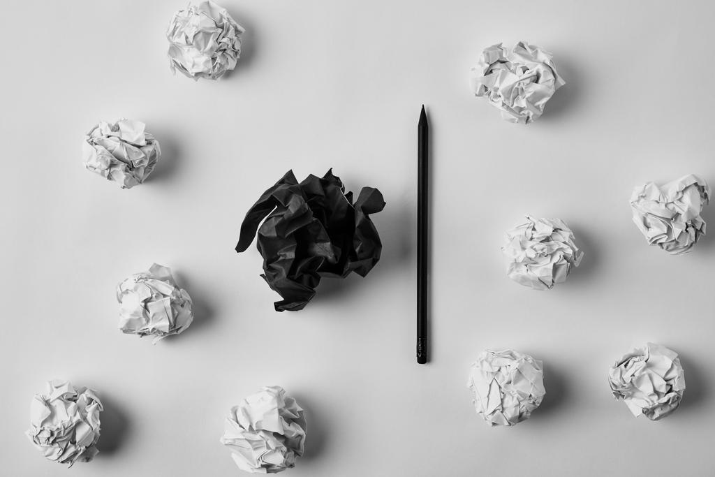 Draufsicht zerknüllter schwarzweißer Papiere mit Bleistift auf weißer Oberfläche - Foto, Bild