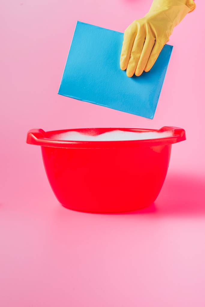 imagem cortada de mulher em luva de borracha espalhando pó de lavagem na bacia de plástico com espuma, fundo rosa
  - Foto, Imagem