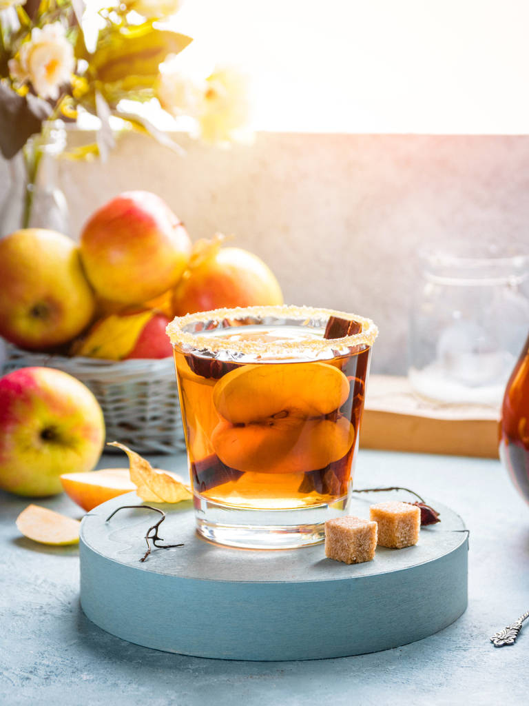 Apple μηλίτη ποτό, ζεστό κοκτέιλ με ραβδιά κανέλας και τις φέτες μήλου. Τσάι με μπαχαρικά. Φθινόπωρο ηλιόλουστο πρωί ζεστή διάθεση. Ρομαντική ατμόσφαιρα. - Φωτογραφία, εικόνα