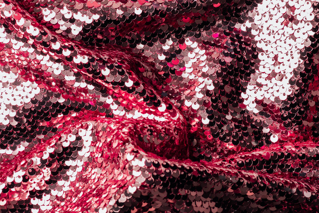 bovenaanzicht van rode en zilveren iriserende textiel met glanzende pailletten als achtergrond  - Foto, afbeelding