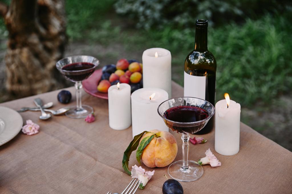 κεριά και κόκκινο κρασί στο τραπέζι στον κήπο - Φωτογραφία, εικόνα