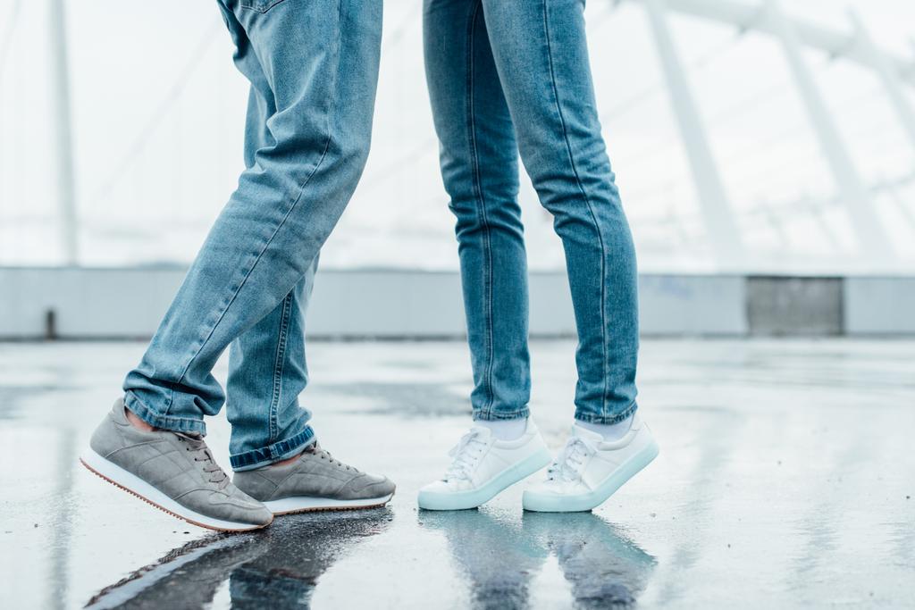 corte tiro de casal em jeans e tênis flertando no estacionamento
 - Foto, Imagem