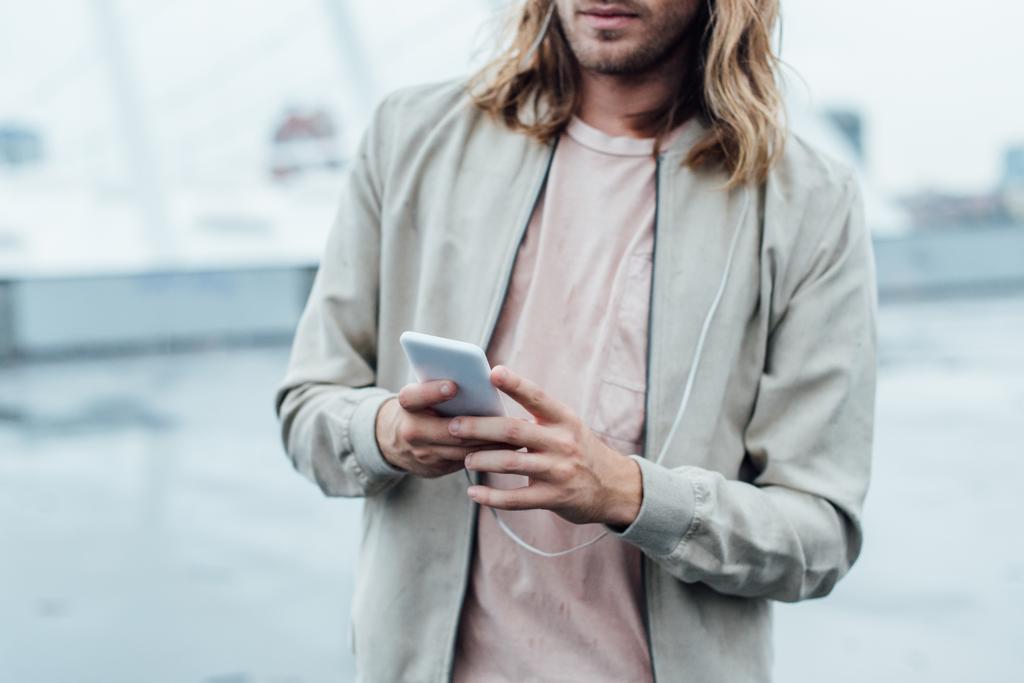 обрізаний знімок молодого чоловіка, використовуючи смартфон на вулиці в похмурий день
 - Фото, зображення