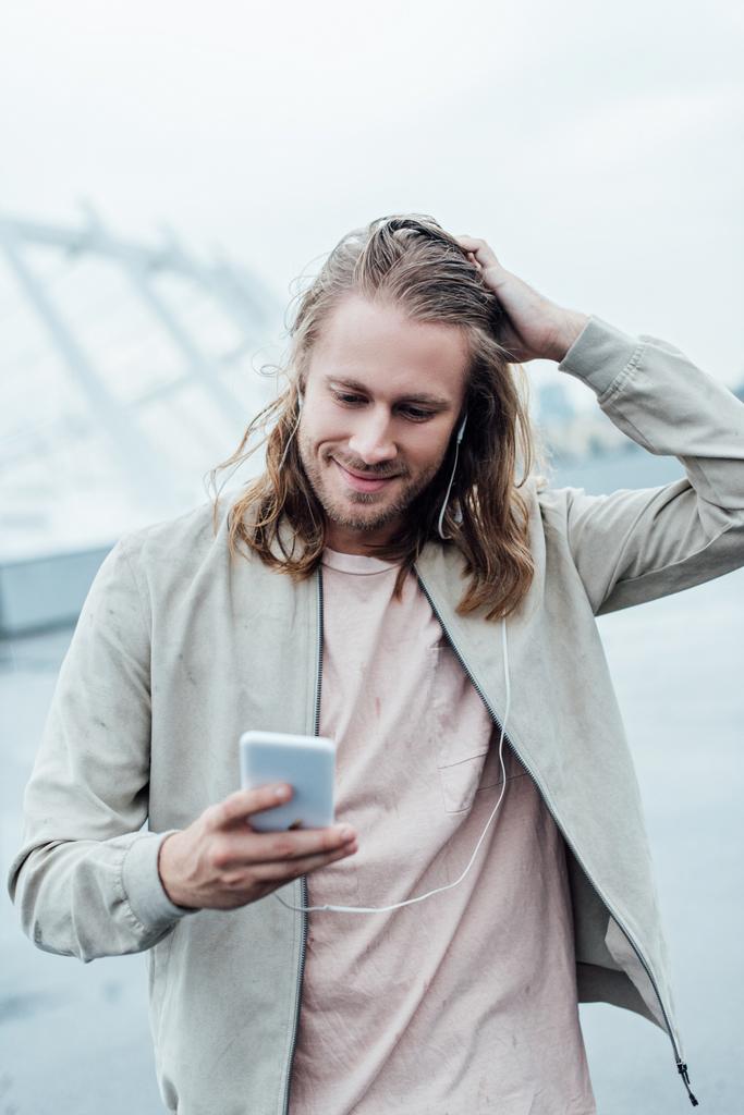 szczęśliwy młody mężczyzna słuchania muzyki z słuchawki i smartphone na ulicy - Zdjęcie, obraz