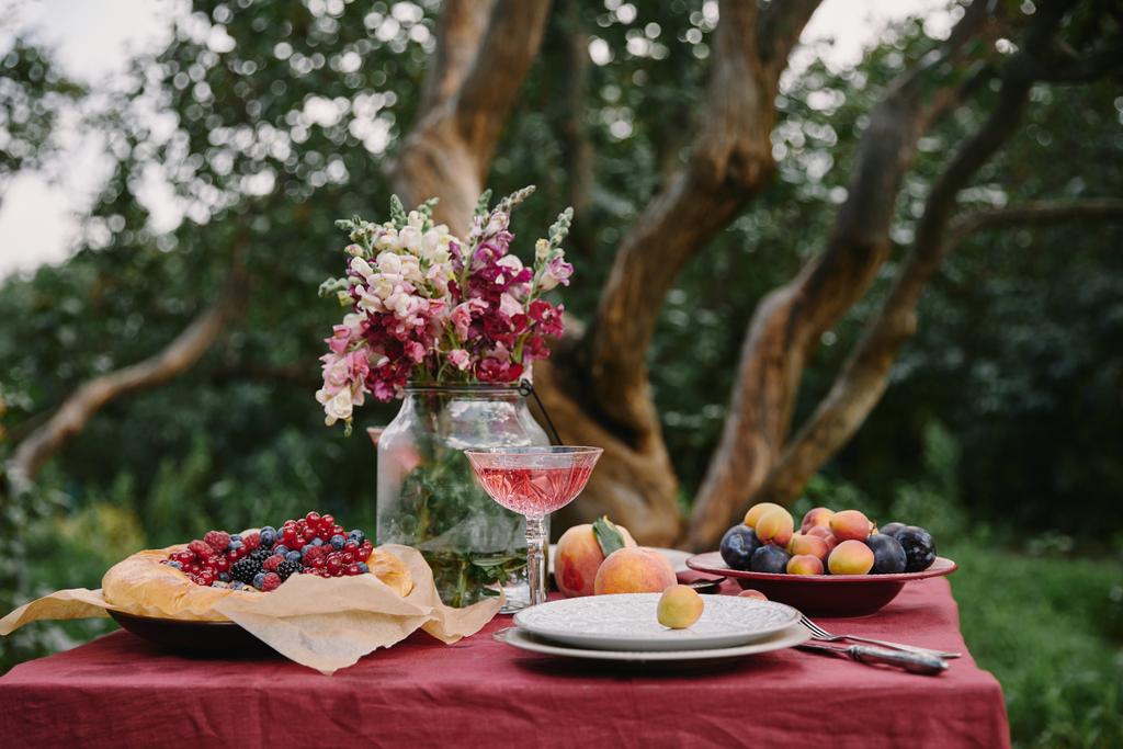 букет цветов, фруктов и вкусный пирог на столе в саду
 - Фото, изображение