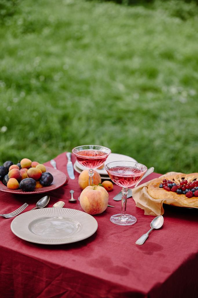 pohár bor, gyümölcs és bogyók pite kerti asztal - Fotó, kép