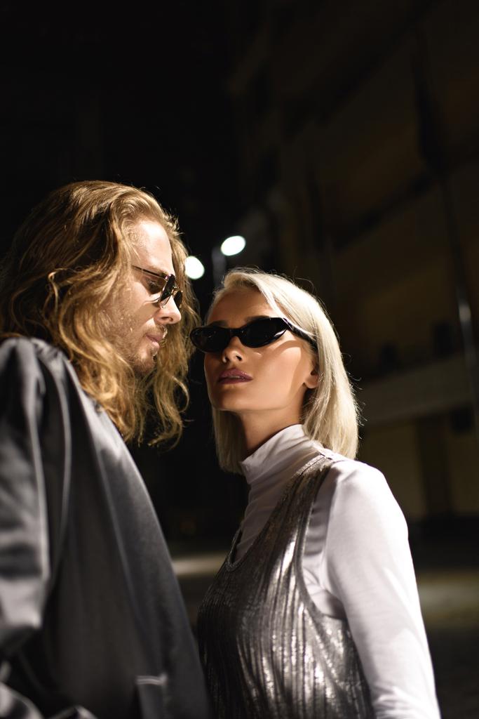 νεαρό ζευγάρι της μόδας στα γυαλιά ηλίου φλερτ στο δρόμο τη νύχτα - Φωτογραφία, εικόνα