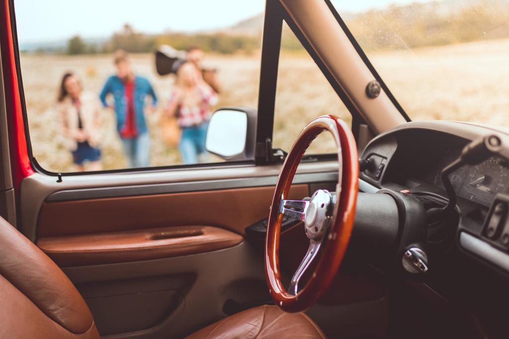 интерьер автомобиля с людьми, идущими по цветочному полю во время автомобильной поездки размыты на заднем плане
 - Фото, изображение