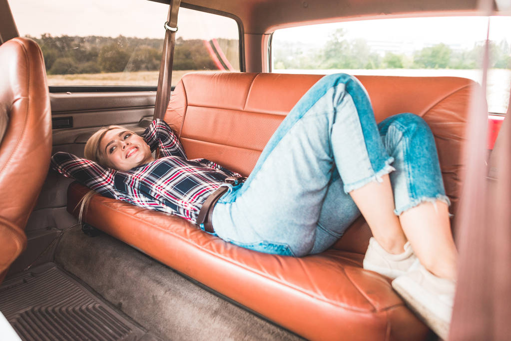 belle jeune femme couchée sur le siège arrière de voiture vintage dans le domaine
 - Photo, image