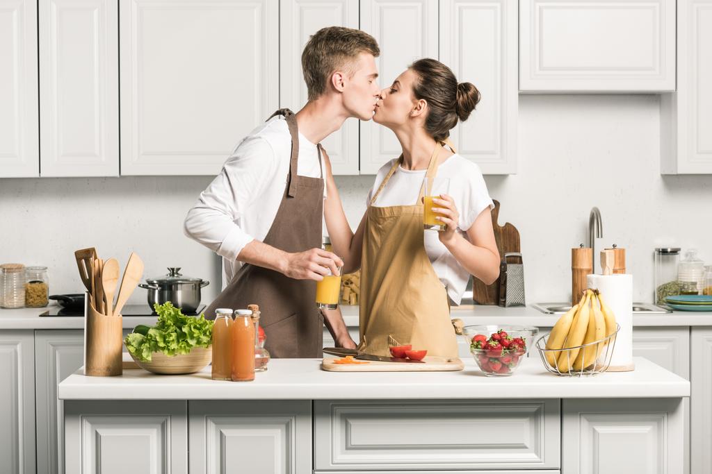 pareja joven besándose mientras cocina ensalada en cocina
 - Foto, imagen