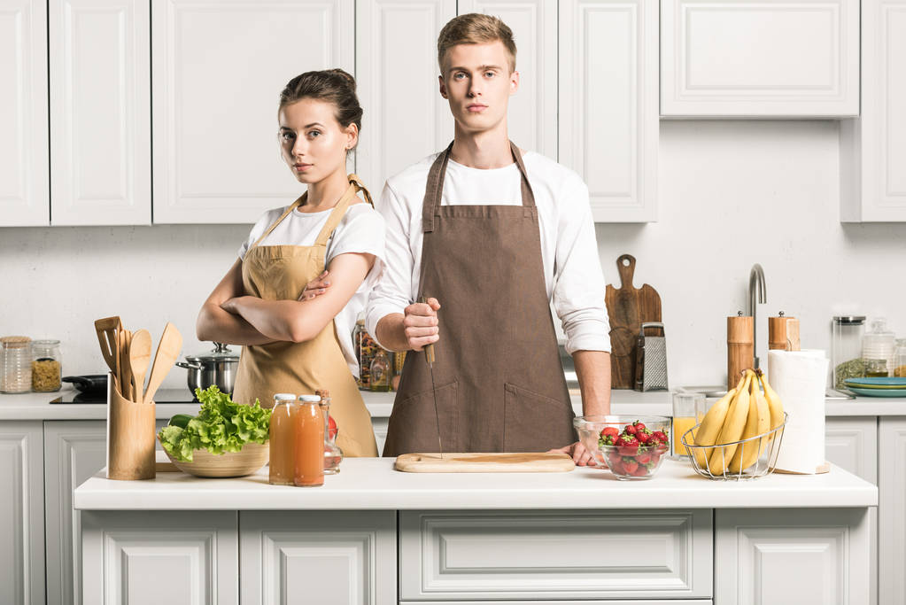 vážný mladý pár při pohledu na fotoaparát v kuchyni - Fotografie, Obrázek