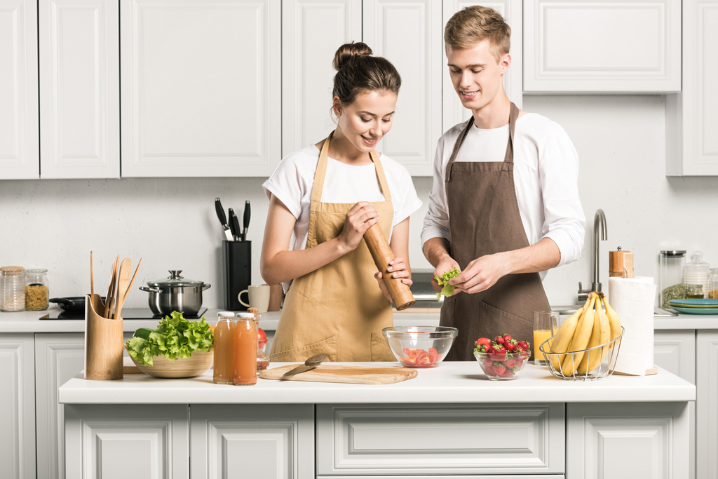 giovane coppia cottura insalata e l'aggiunta di spezie in cucina
 - Foto, immagini