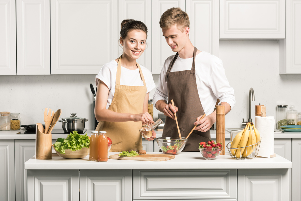 pareja joven cocinando ensalada saludable en la cocina
 - Foto, Imagen