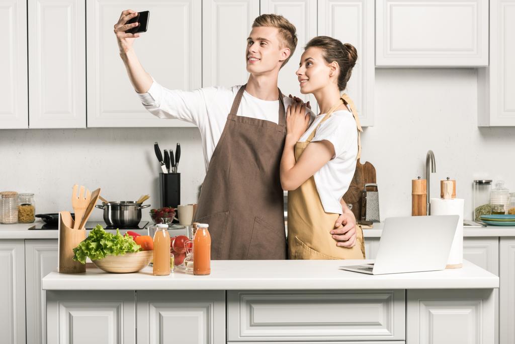 jovem casal tomando selfie com smartphone na cozinha
 - Foto, Imagem