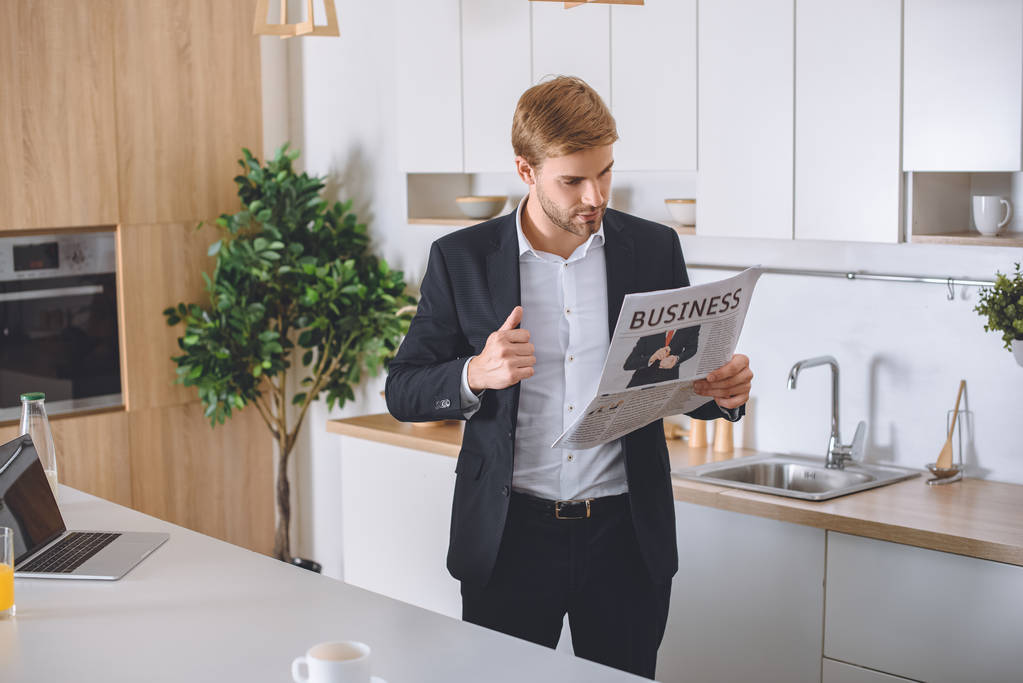 joven hombre de negocios leyendo periódico de negocios en la cocina
  - Foto, imagen